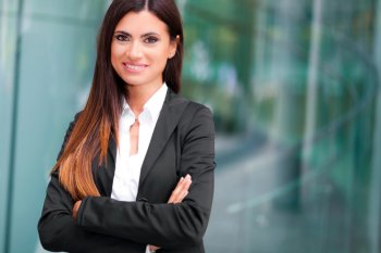 Eine Geschäftsfrau im Anzug verschränkt die Arme und lächelt in die Kamera