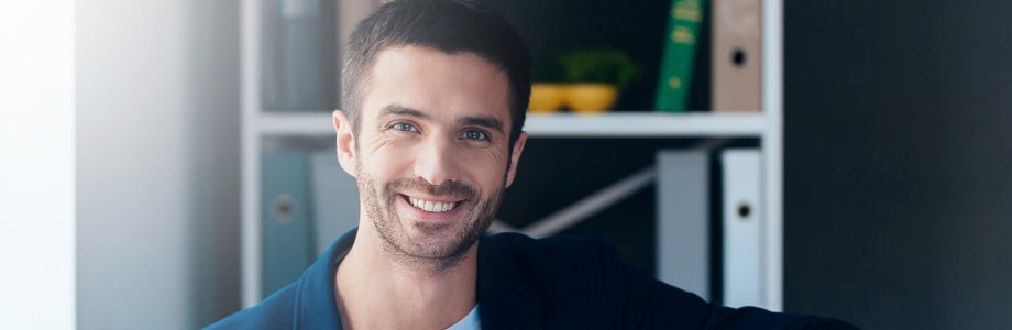 Ein Projektleiter sitzt auf einer Couch und lächelt in die Kamera