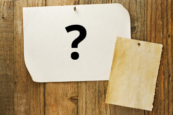 Zwei Notizzettel sind an eine Wand gepinnt. Auf einem ist ein großes Fragezeichen