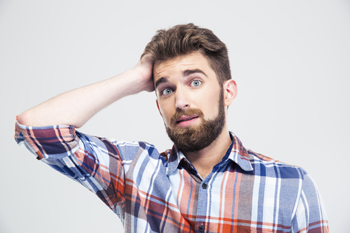 junger Mann mit besorgtem Blick fasst sich an den Kopf