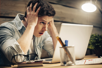 junger Mann verzweifelt vor Laptop