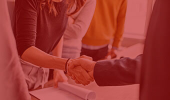 Mann und Frau geben sich über Schreibtisch die Hand