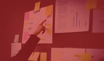 Studentin zeigt auf eine Wand mit Klebezetteln und Grafiken.