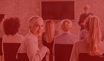 Frau sitzt in einer Lerngruppe und lächelt in die Kamera.