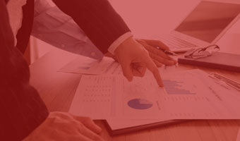 Finger zeigt auf Geschäftsunterlagen und einen Laptop.